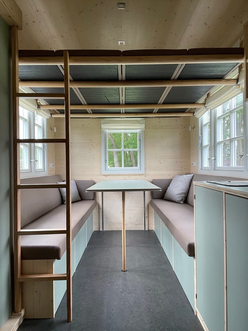 Gemütlicher Wohnbereich im Bauwagen mit Sitzecke aus Naturholz raus in den Bauwagen